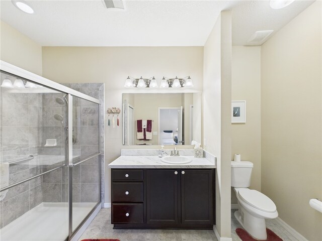 bathroom with visible vents, a stall shower, baseboards, toilet, and vanity