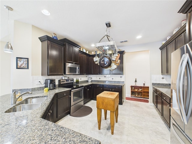 kitchen with visible vents, a sink, stainless steel appliances, dark brown cabinetry, and light stone countertops