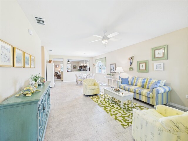 living room with light tile patterned flooring, ceiling fan, visible vents, and baseboards