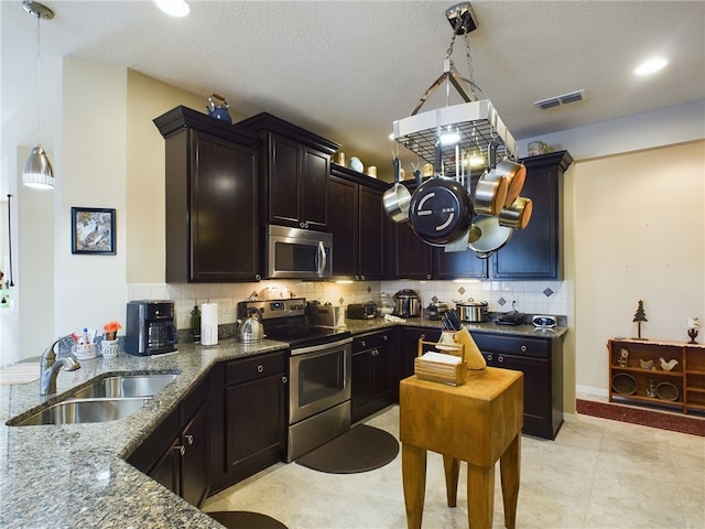 kitchen with sink, hanging light fixtures, appliances with stainless steel finishes, dark stone counters, and backsplash