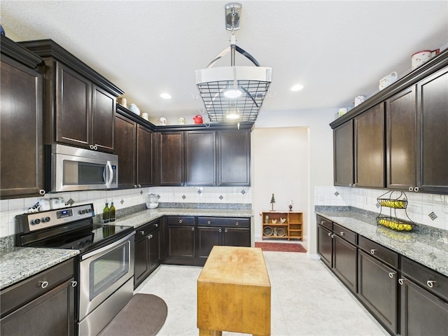 kitchen featuring backsplash, light stone countertops, dark brown cabinetry, hanging light fixtures, and stainless steel appliances