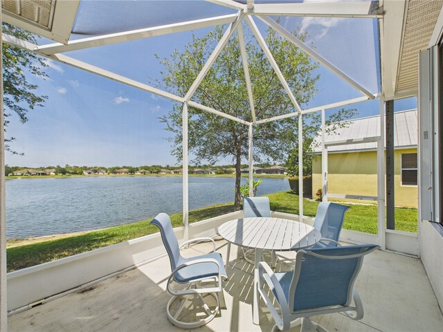 view of patio featuring a lanai, outdoor dining space, and a water view