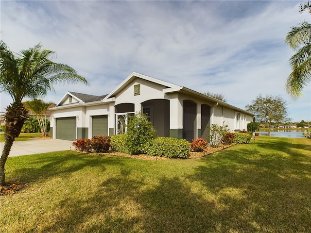 view of front of house featuring driveway, stucco siding, a front lawn, a water view, and a garage