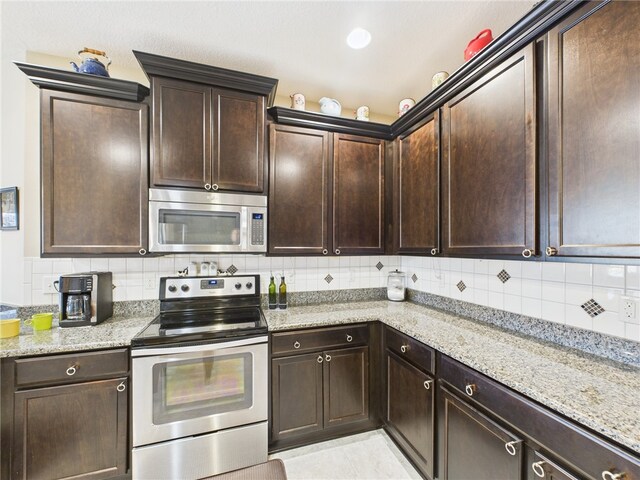 kitchen with dark brown cabinets, ceiling fan, stainless steel appliances, light stone countertops, and decorative backsplash