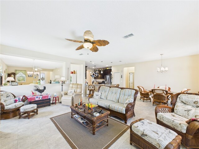living room with light tile patterned floors, visible vents, and ceiling fan with notable chandelier
