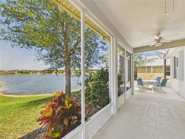 unfurnished sunroom with ceiling fan and a water view