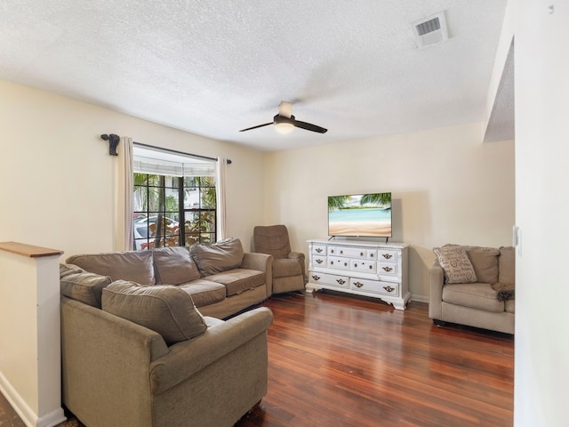 living room with dark wood-type flooring, ceiling fan, and a textured ceiling