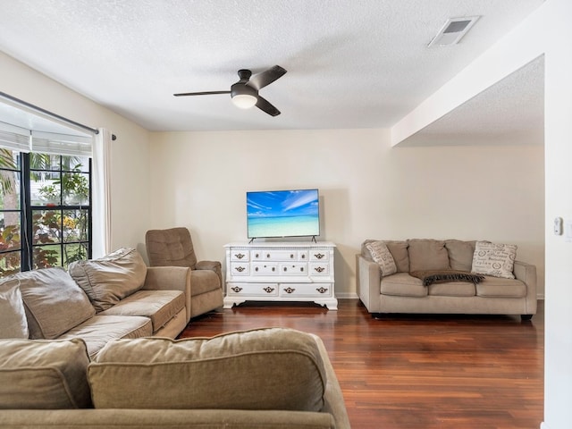 living room with a textured ceiling, dark wood-type flooring, and ceiling fan