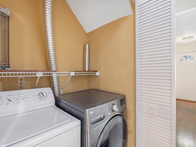 clothes washing area featuring washing machine and dryer, a textured ceiling, and wood-type flooring