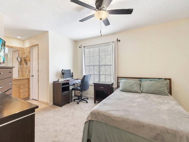 carpeted bedroom featuring a textured ceiling, ensuite bath, and ceiling fan