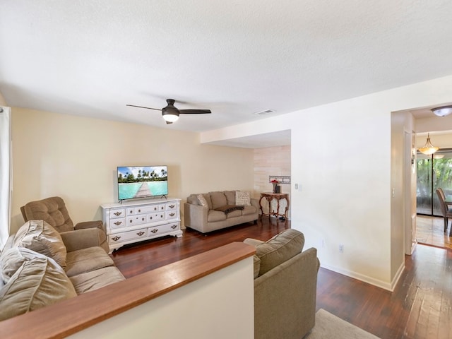 living room featuring ceiling fan, a textured ceiling, and dark hardwood / wood-style flooring