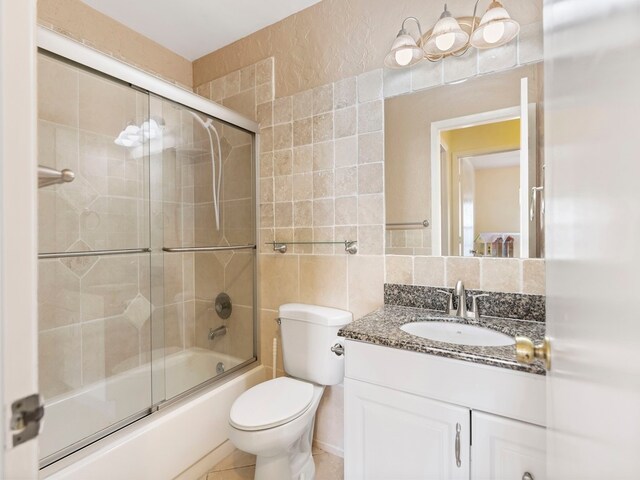 full bathroom featuring tile walls, backsplash, vanity, bath / shower combo with glass door, and toilet