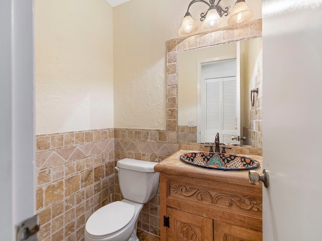 bathroom featuring toilet, vanity, and tile walls