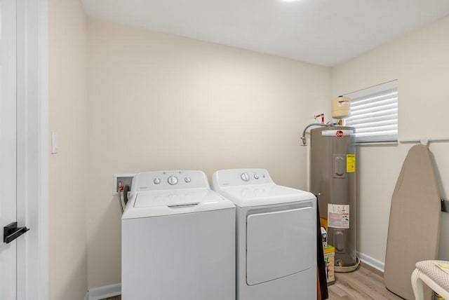 clothes washing area featuring water heater, washing machine and dryer, light wood-type flooring, laundry area, and baseboards