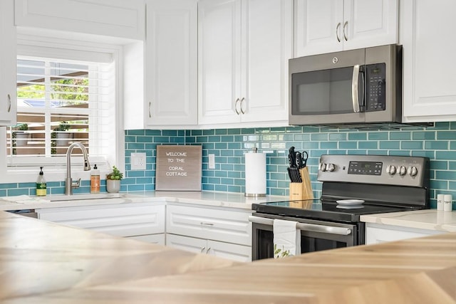 kitchen featuring stainless steel appliances, light countertops, backsplash, white cabinetry, and a sink