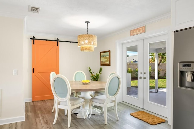 dining area with a barn door, visible vents, ornamental molding, french doors, and light wood-style floors