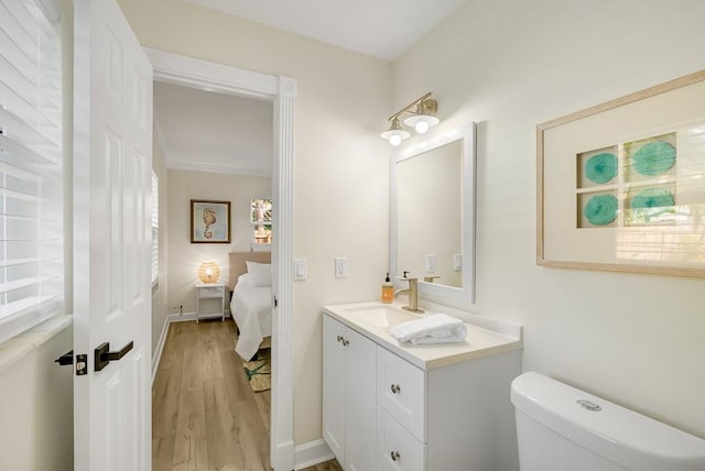 bathroom with baseboards, vanity, toilet, and wood finished floors