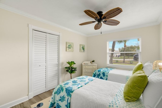 bedroom featuring ceiling fan, wood finished floors, baseboards, ornamental molding, and a closet