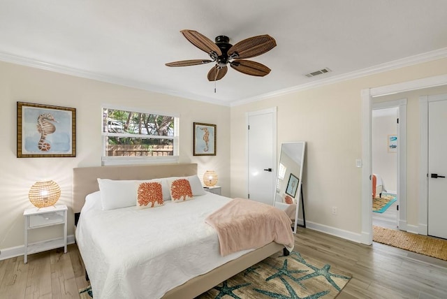 bedroom featuring light wood-type flooring, visible vents, crown molding, and baseboards