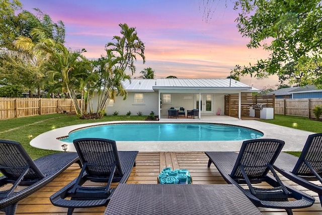 pool at dusk featuring a fenced in pool, french doors, a fenced backyard, and a yard