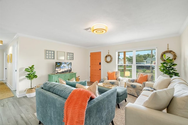 living room featuring light wood-style floors, visible vents, ornamental molding, and baseboards