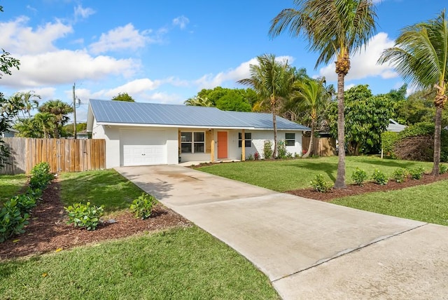 ranch-style home featuring an attached garage, fence, driveway, stucco siding, and a front lawn