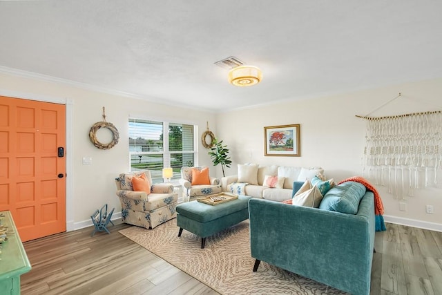 living room featuring ornamental molding, wood finished floors, visible vents, and baseboards