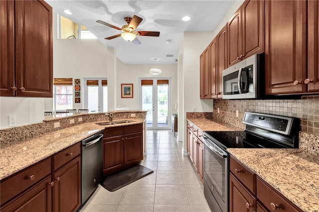 kitchen featuring stainless steel appliances, a sink, backsplash, and light stone counters