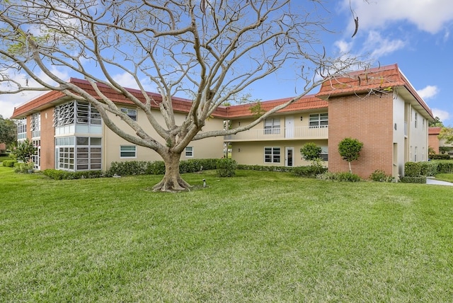 41 Woodland Dr Unit 102, Vero Beach, FL 32962 - back of house with a tile roof, a lawn, and stucco siding