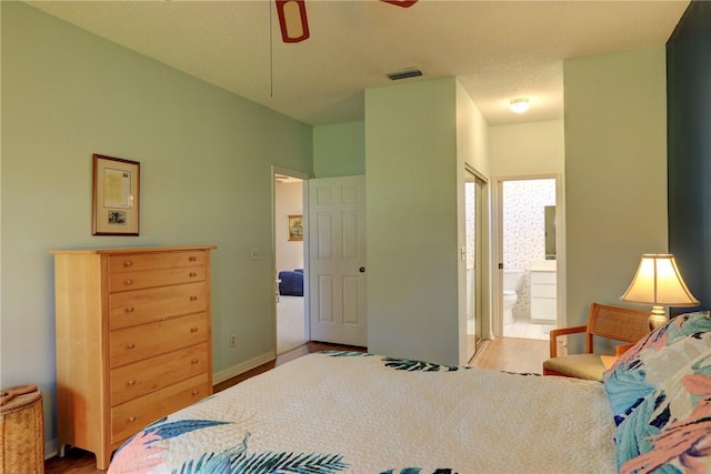 bedroom with ceiling fan, light hardwood / wood-style flooring, and ensuite bath