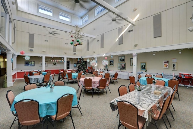 carpeted dining room with ceiling fan and a towering ceiling