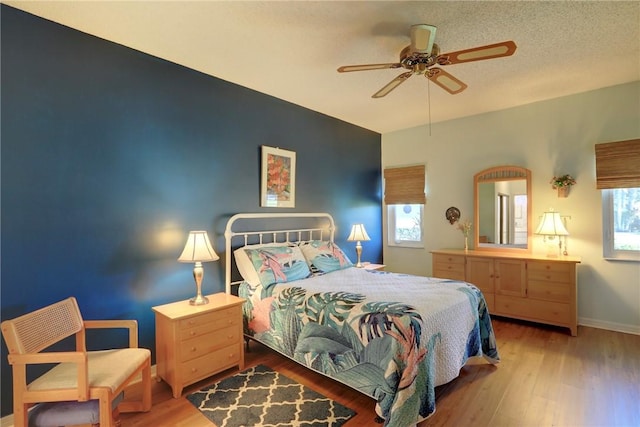 bedroom with a textured ceiling, hardwood / wood-style flooring, and ceiling fan