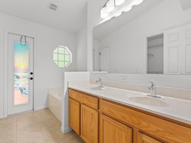 bathroom featuring tile patterned flooring, vanity, vaulted ceiling, and a washtub