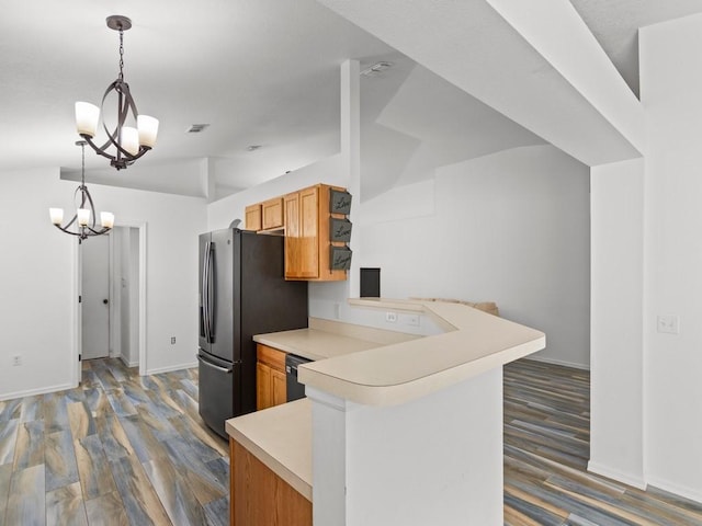 kitchen with kitchen peninsula, stainless steel fridge, dark wood-type flooring, a chandelier, and hanging light fixtures