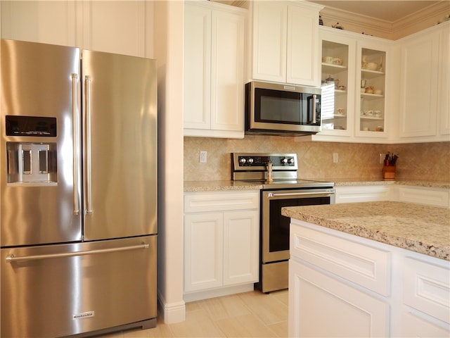 kitchen featuring white cabinetry, appliances with stainless steel finishes, light stone counters, and backsplash