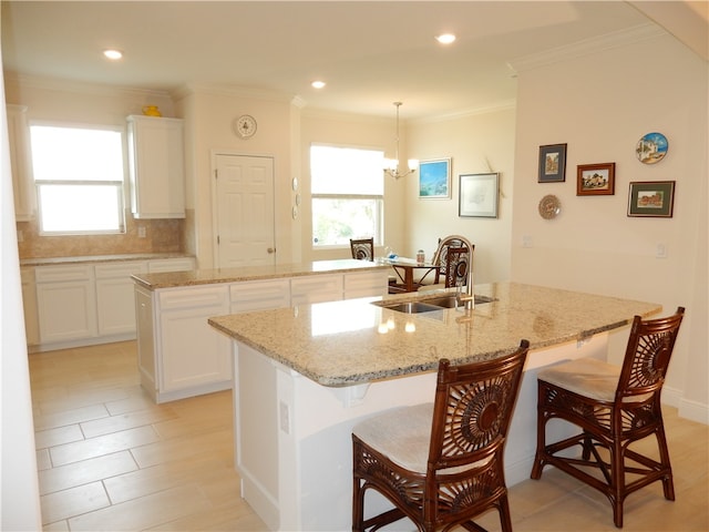 kitchen with white cabinets, a wealth of natural light, and a center island with sink