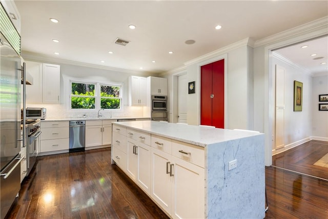 kitchen featuring a kitchen island, tasteful backsplash, sink, white cabinets, and light stone countertops