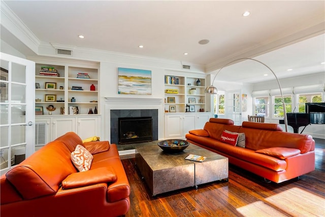 living room with dark hardwood / wood-style flooring, crown molding, a fireplace, and built in shelves