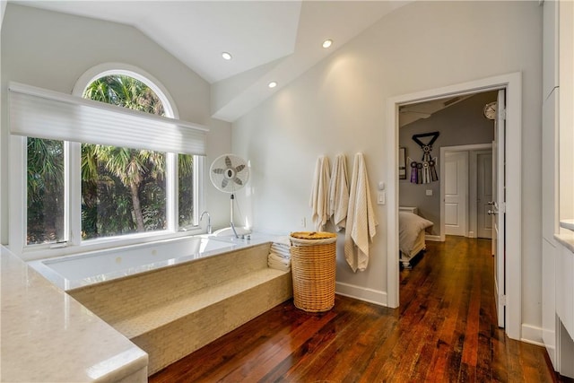 bathroom with vaulted ceiling, a bathing tub, and wood-type flooring