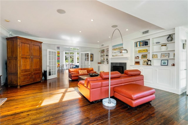 living room with a tiled fireplace, crown molding, dark hardwood / wood-style flooring, and french doors