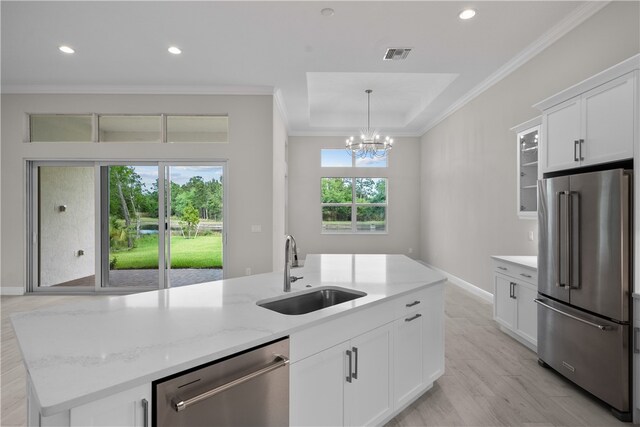 kitchen with a wealth of natural light, appliances with stainless steel finishes, sink, and white cabinets