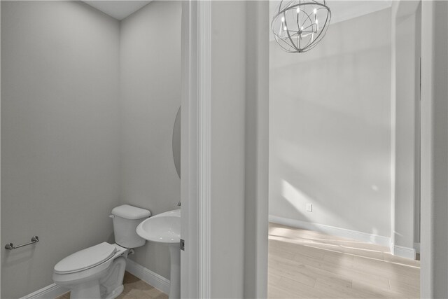 bathroom with wood-type flooring, a chandelier, and toilet