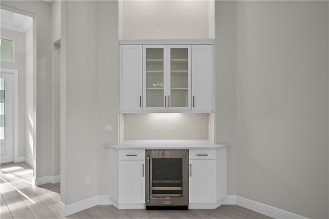 bar with white cabinetry, wine cooler, light wood-type flooring, and tasteful backsplash