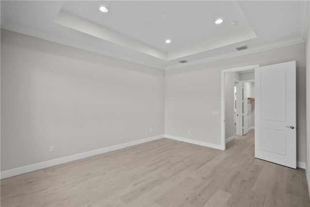 unfurnished room with light hardwood / wood-style flooring, crown molding, and a tray ceiling