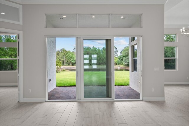 doorway with light wood-type flooring, a chandelier, and crown molding