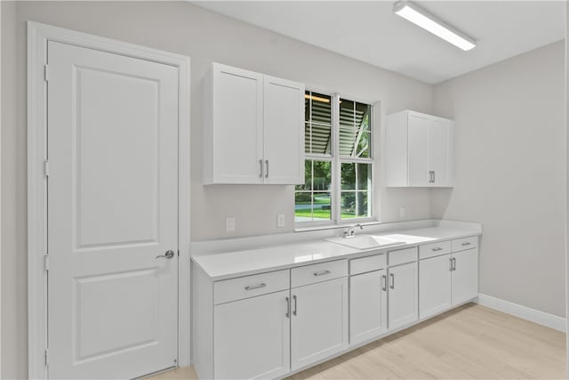 kitchen with white cabinetry, sink, and light hardwood / wood-style floors