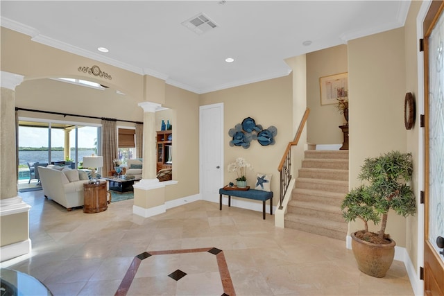 foyer entrance with light tile patterned flooring, decorative columns, a water view, and ornamental molding