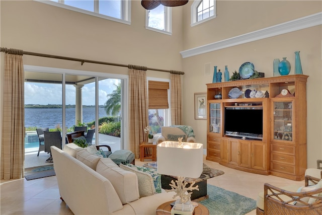 tiled living room with a towering ceiling, a water view, and a healthy amount of sunlight