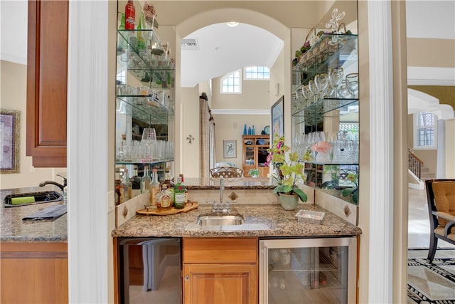 bar featuring beverage cooler, sink, and light stone countertops