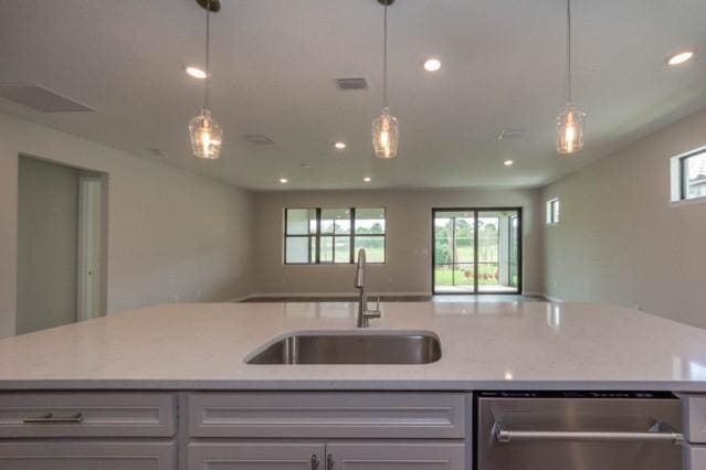 kitchen with decorative light fixtures, sink, stainless steel dishwasher, and a kitchen island with sink